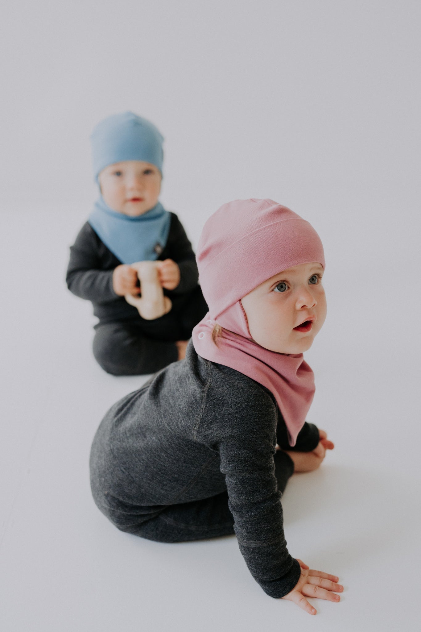 2 kids with baby hats. one is blue hat, other is pink breden baby hat