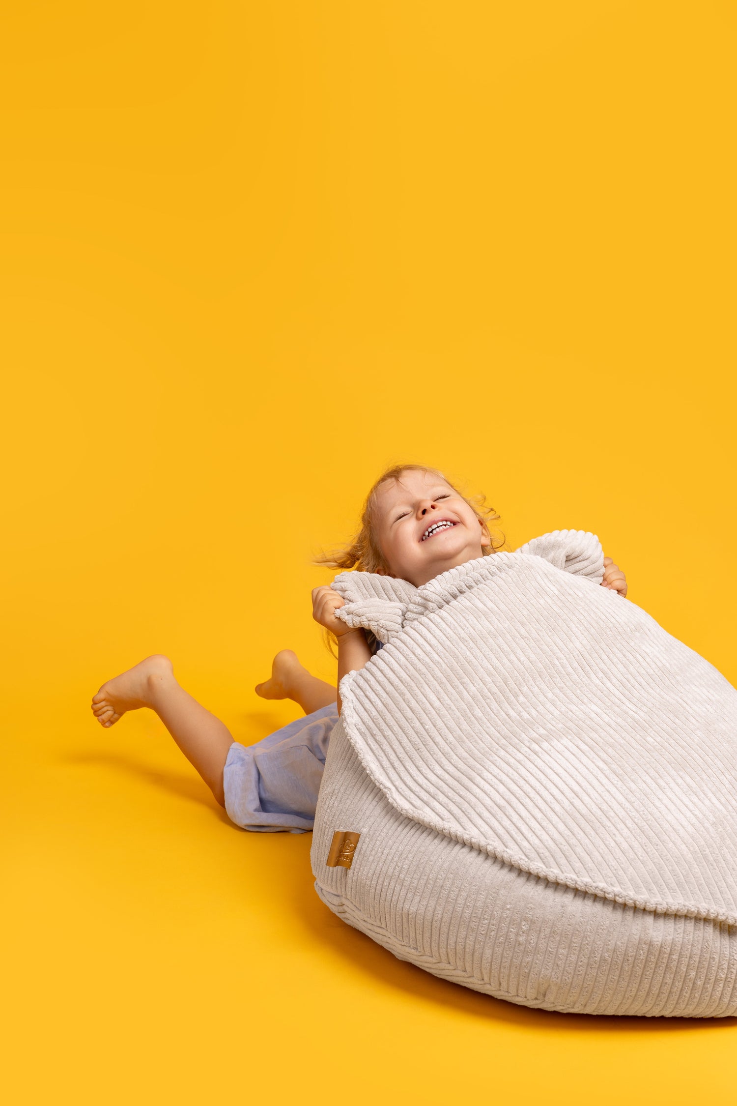 little girl playing with her beige sako bag on orange background