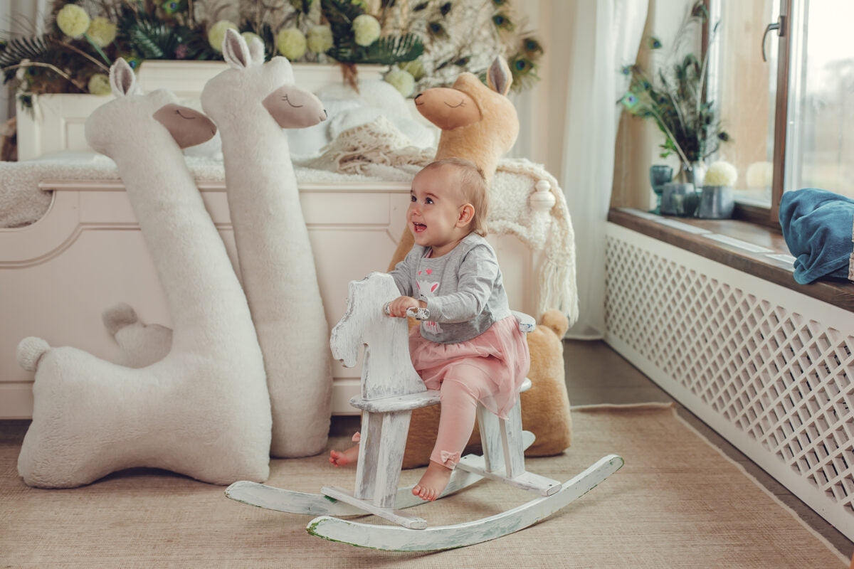 a baby on a rocker next to her 3 alppaca soft pillows