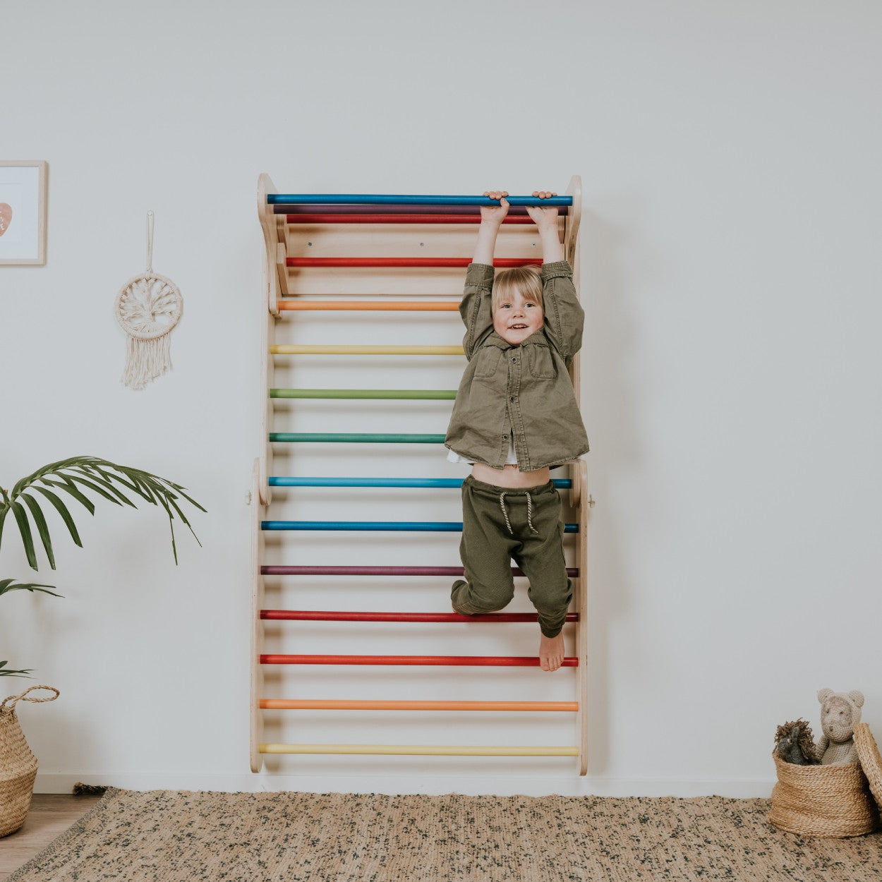 kid hanging from a pastel color leg&go swedish wall